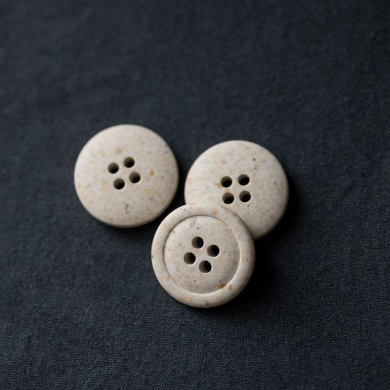 20mm recycled resin button with 4 holes. Off white with warm speckles. (Also available in black.) These buttons are made with 50-60% biodegradable vegetable fibres. Sold individually. Made in Italy.