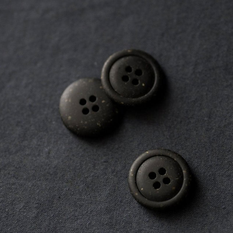20mm recycled resin button with 4 holes. Black with warm speckles. (Also available in off white.) These buttons are made with 50-60% biodegradable vegetable fibres. Sold individually. Made in Italy.