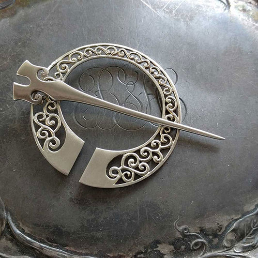 Runa Penannular Brooch by JUL Designs. Available in two options: white brass and blackened white brass. This beautiful penannular brooch is inspired by Norse designs that make liberal use of spiral motifs. The shape of Norse helmets have been the inspiration to create the stick portion of this pin. Hand-made Fair Trade