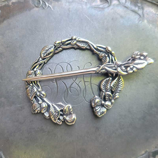 Sweet Pea Penannular Brooch by JUL Designs  White brass  Inside diameter: 38mm (1.5") Outside diameter: 57mm (2.25")  This lovely penannular brooch is infused with a loose ambiance of Art Nouveau. It has flowers, foliage and sinuous vines of the Sweet Pea. 