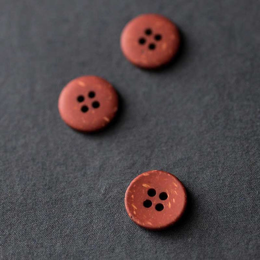 18mm recycled resin button with 4 holes. Available in the following colours: Brick, Ink and Olive. These buttons are made from 10% wooden wastage. Sold individually. Made in Italy. Depicted here in Brick.